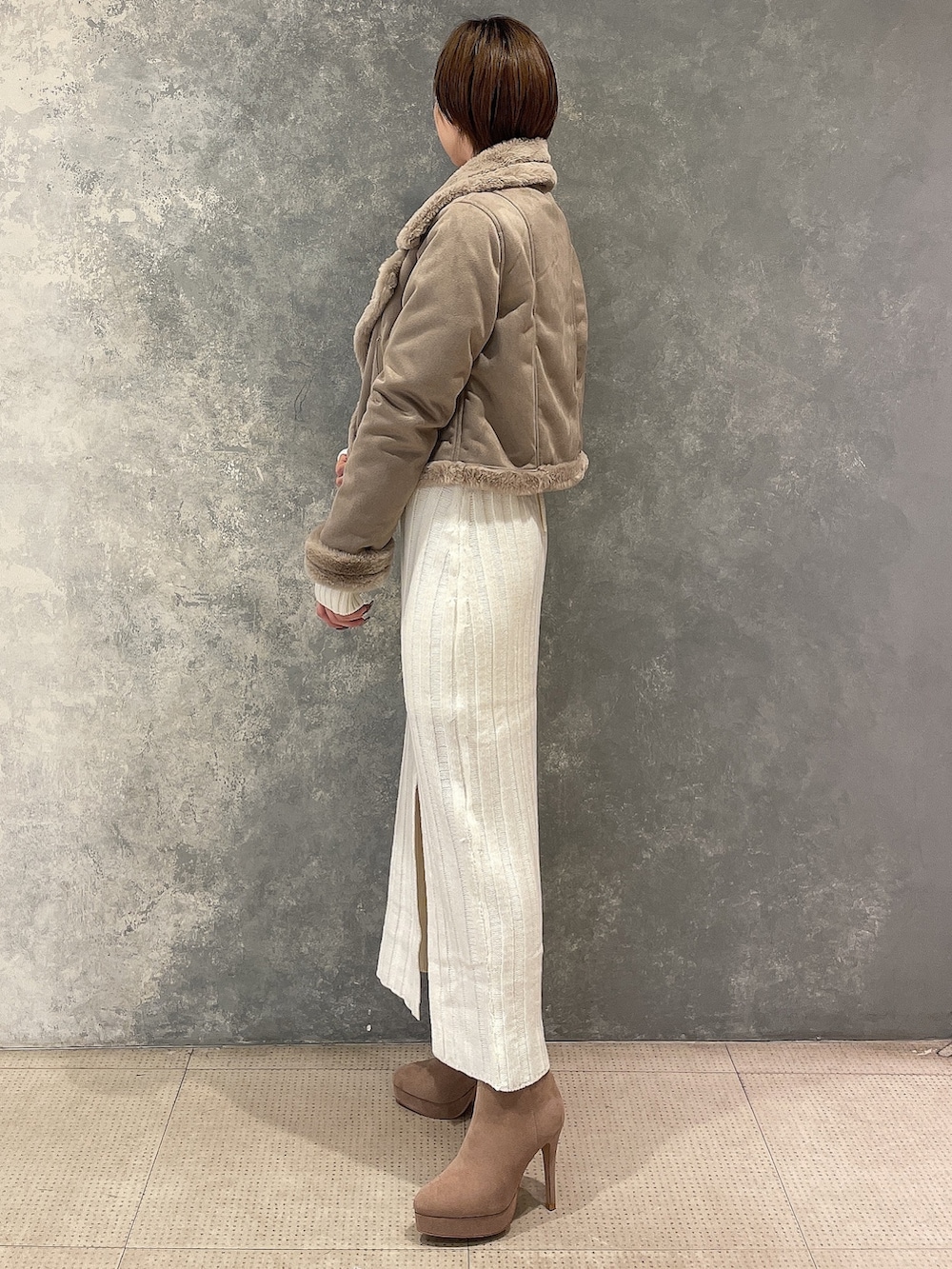 ベージュ系のブルゾン、ホワイト系のワンピース、ベージュ系のブーツを着用したレディースの秋コーディネートの3枚目の写真