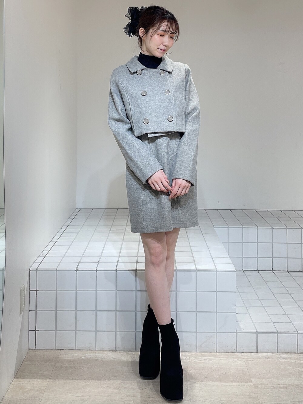 グレー系のその他アウター、グレー系のジャンパースカート、ブラック系のニット/セーターを着用したレディースの冬コーディネートの2枚目の写真