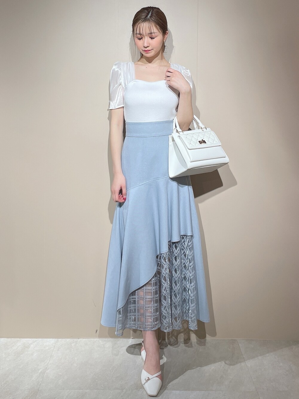 ホワイト系のニット/セーター、ブルー系のスカートを着用したレディースの春コーディネートの2枚目の写真