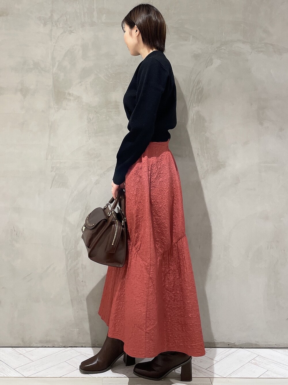 ベージュ系のダウンジャケット/コート、ブラック系のニット/セーター、ブラウン系のハンドバッグを着用したレディースの秋コーディネートの5枚目の写真