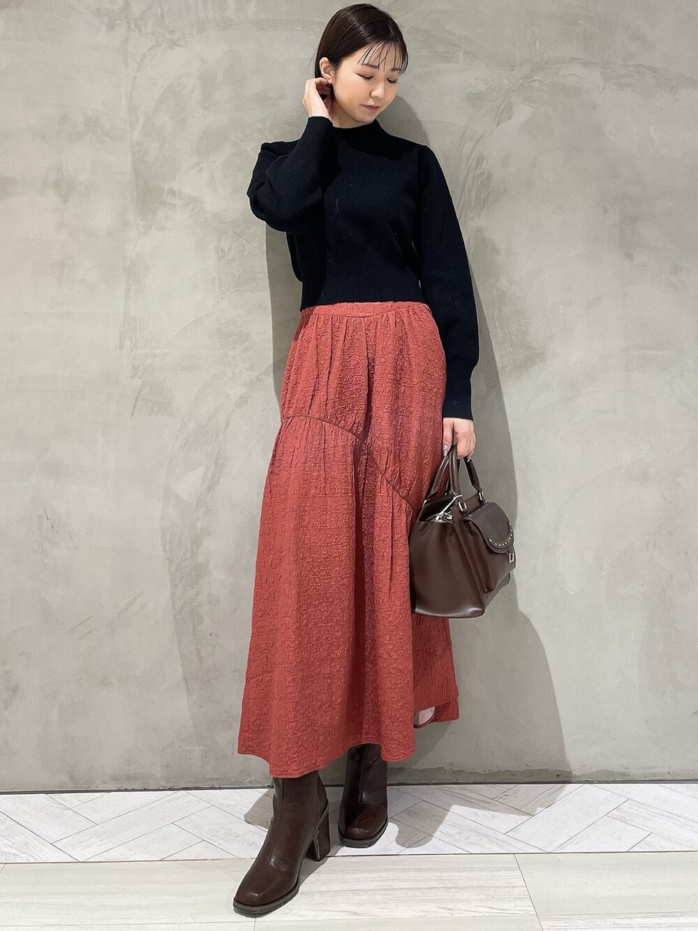 ベージュ系のダウンジャケット/コート、ブラック系のニット/セーター、ブラウン系のハンドバッグを着用したレディースの秋コーディネートの4枚目の写真