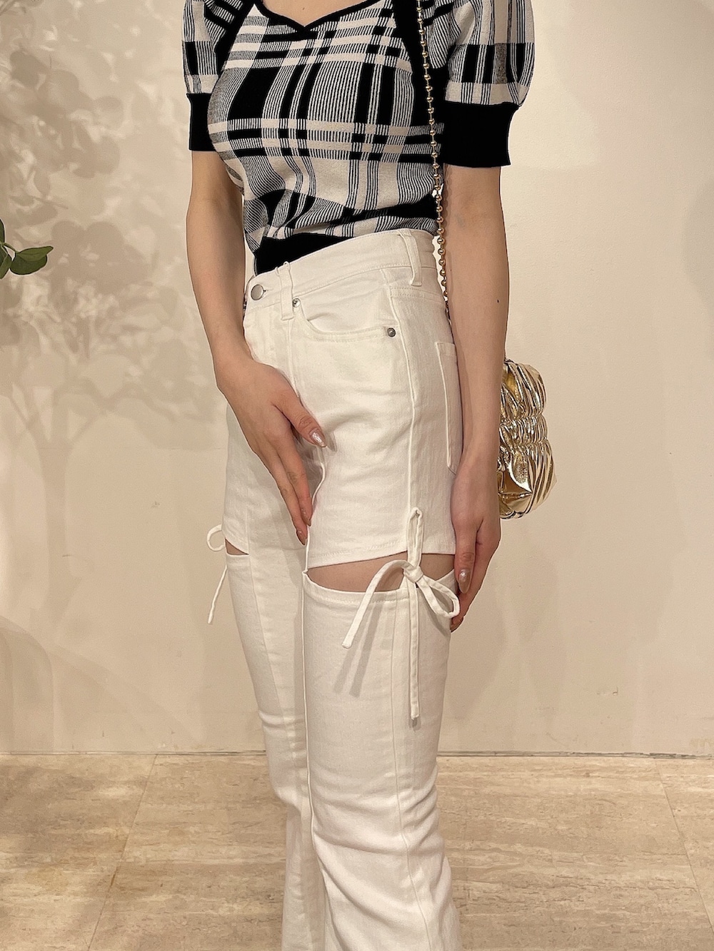 ブラック系のニット/セーター、ホワイト系のデニムパンツ、ゴールド系のハンドバッグを着用したレディースの春コーディネートの7枚目の写真