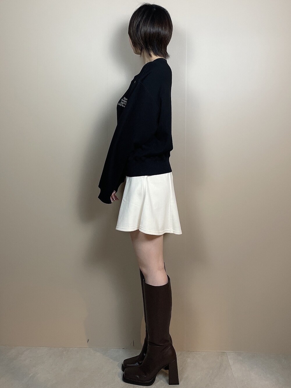 ホワイト系のスカート、ブラウン系のブーツ、ブラック系のスウェットを着用したレディースの夏コーディネートの3枚目の写真
