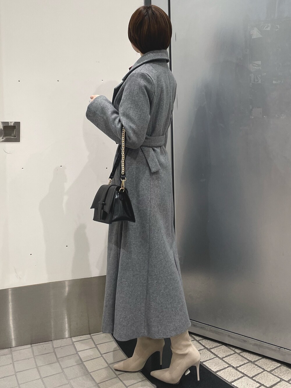 ホワイト系のブーツ、ブラック系のハンドバッグ、グレー系のその他アウターを着用したレディースの冬コーディネートの3枚目の写真