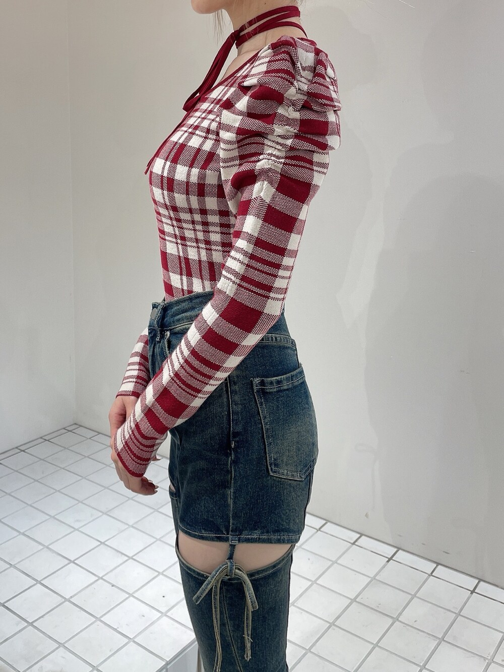 レッド系のニット/セーター、ブルー系のデニムパンツ、ブラック系のブーツを着用したレディースの秋コーディネートの7枚目の写真