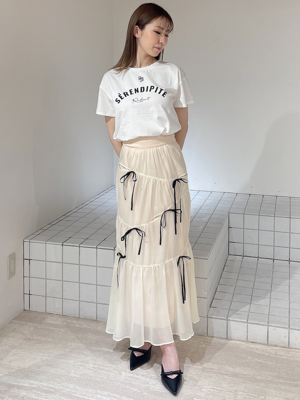 ホワイト系のTシャツ/カットソー、ホワイト系のスカート、ブラック系のパンプスを着用したレディースの夏コーディネートの2枚目の写真