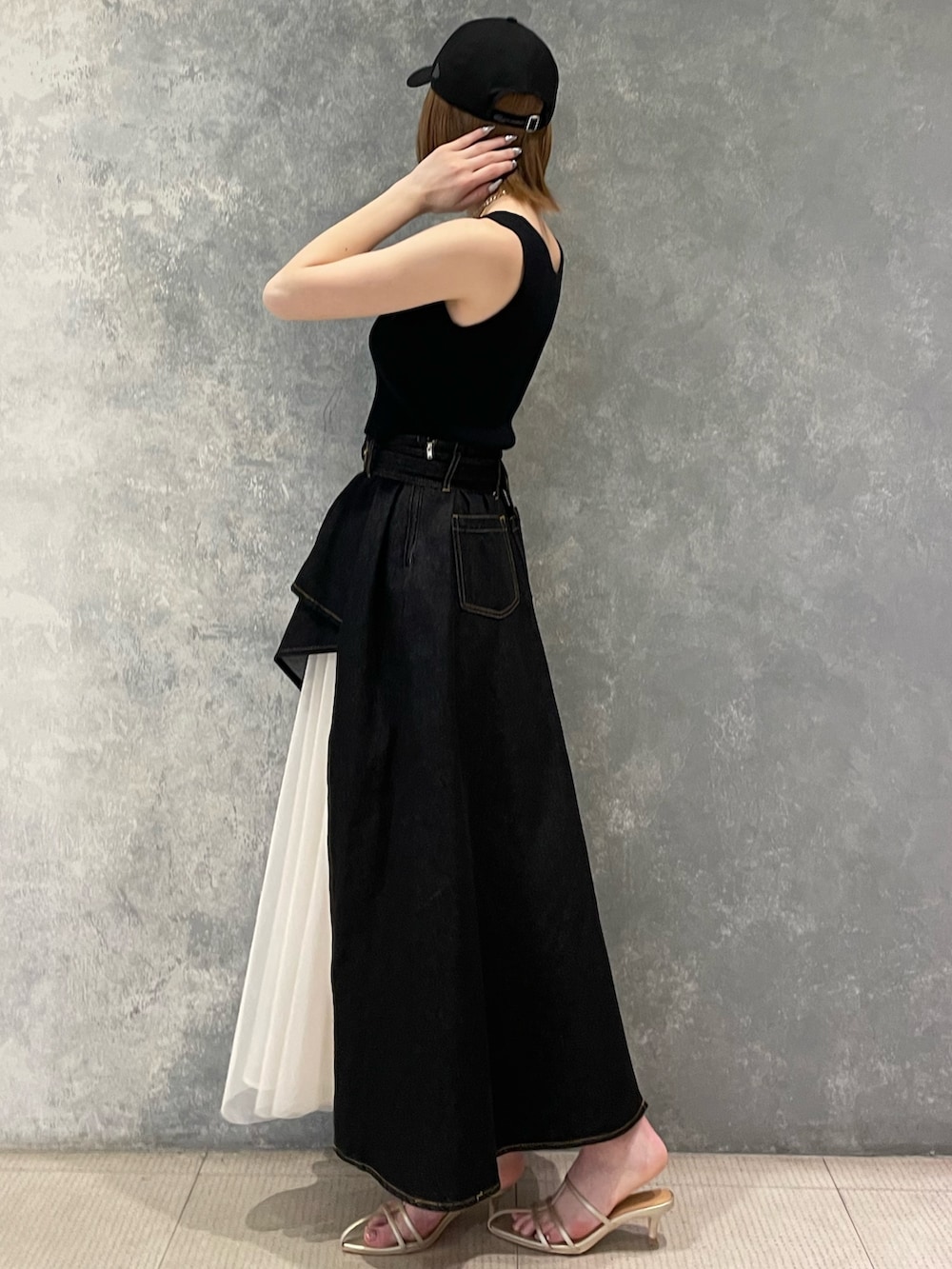 ブラック系のタンクトップ、ブラック系のデニムスカート、ゴールド系のサンダルを着用したレディースの春コーディネートの3枚目の写真