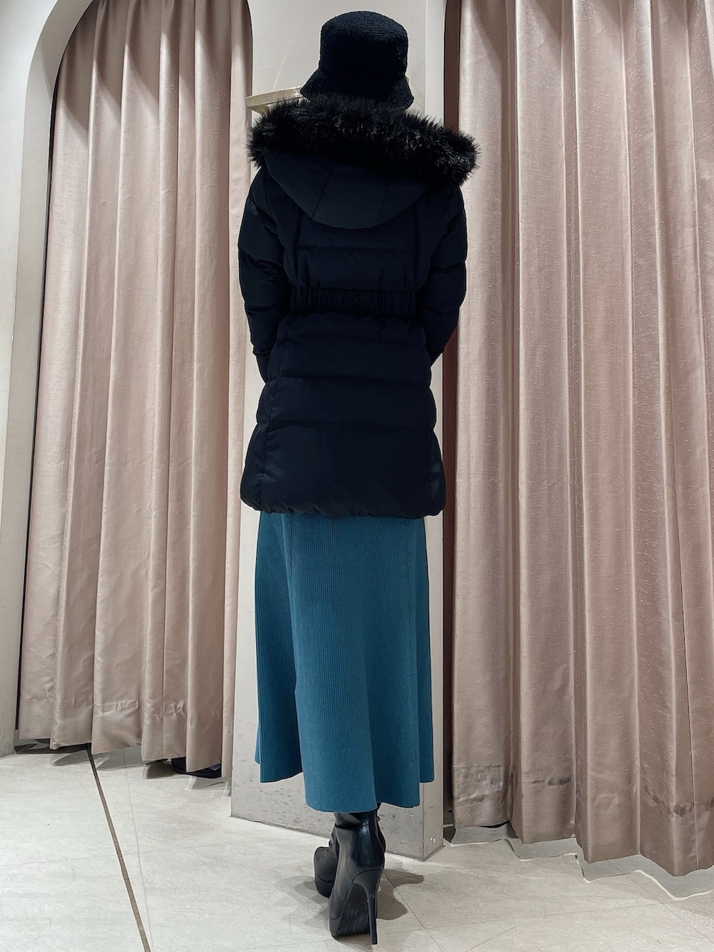 ブルー系のワンピース、ブラック系のブーツ、ブラック系のハットを着用したレディースの冬コーディネートの6枚目の写真