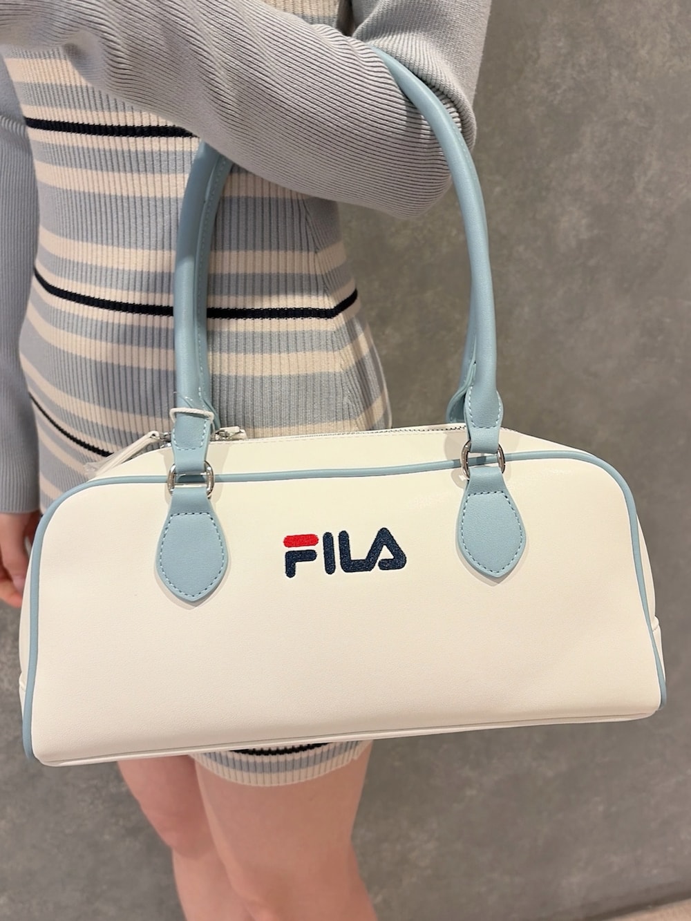 ホワイト系のブーツ、ブルー系のボストンバッグ、ブルー系のワンピースを着用したレディースの冬コーディネートの7枚目の写真