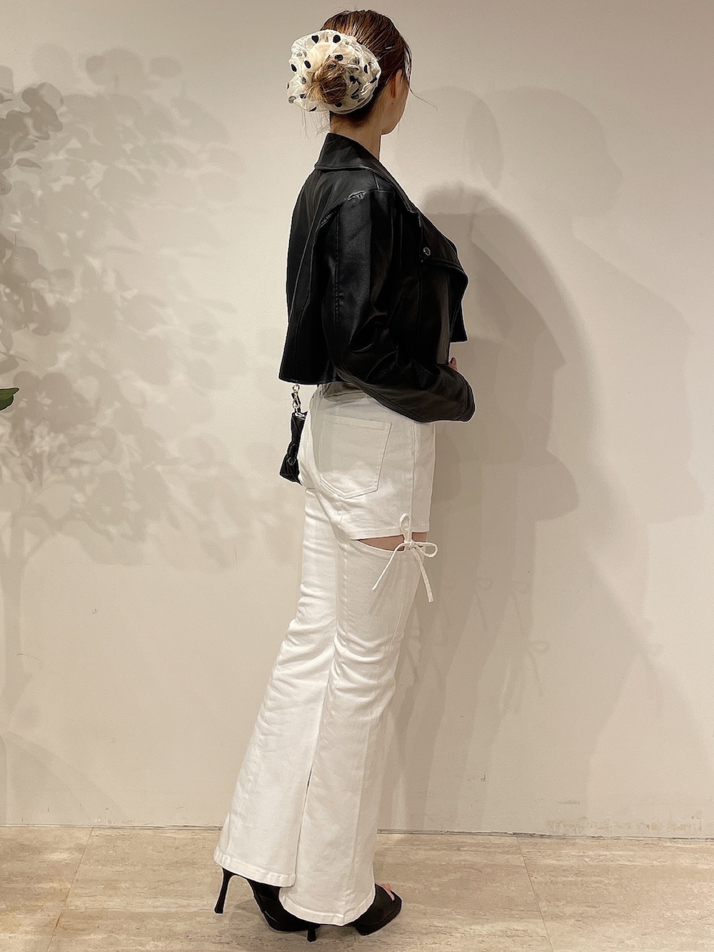 ブラック系のライダースジャケット、ホワイト系のデニムパンツ、ブラック系のブーツを着用したレディースの春コーディネートの3枚目の写真