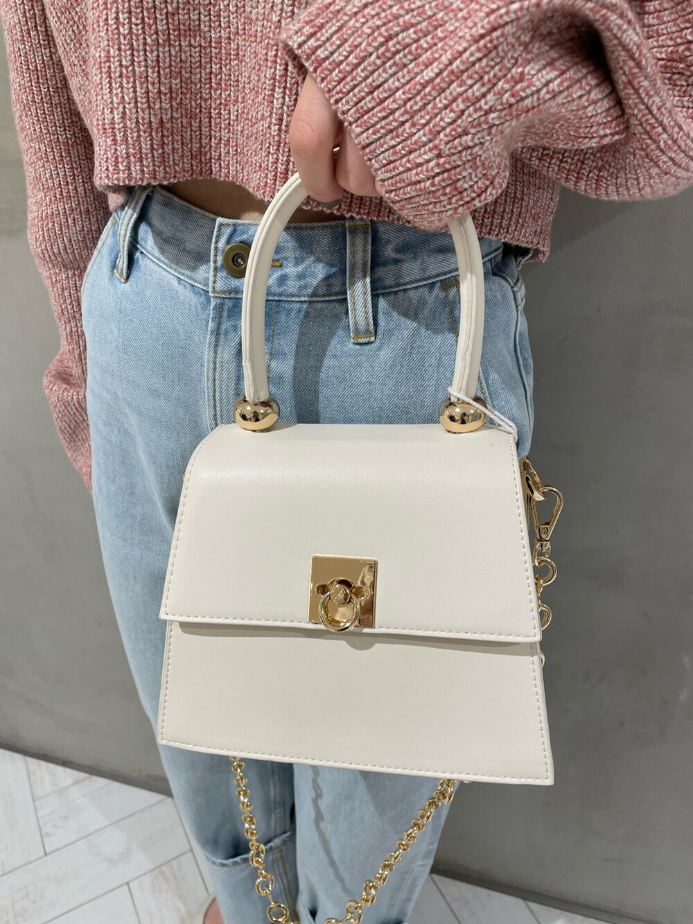 ピンク系のニット/セーター、ホワイト系のハンドバッグ、ブルー系のデニムパンツを着用したレディースの冬コーディネートの8枚目の写真