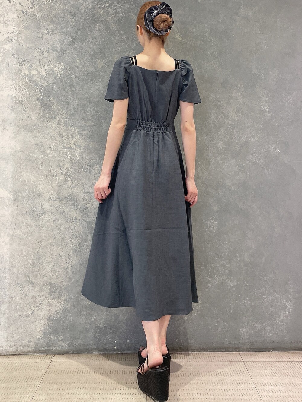 グレー系のワンピース、ブラック系のサンダル、グレー系のシュシュを着用したレディースの夏コーディネートの6枚目の写真