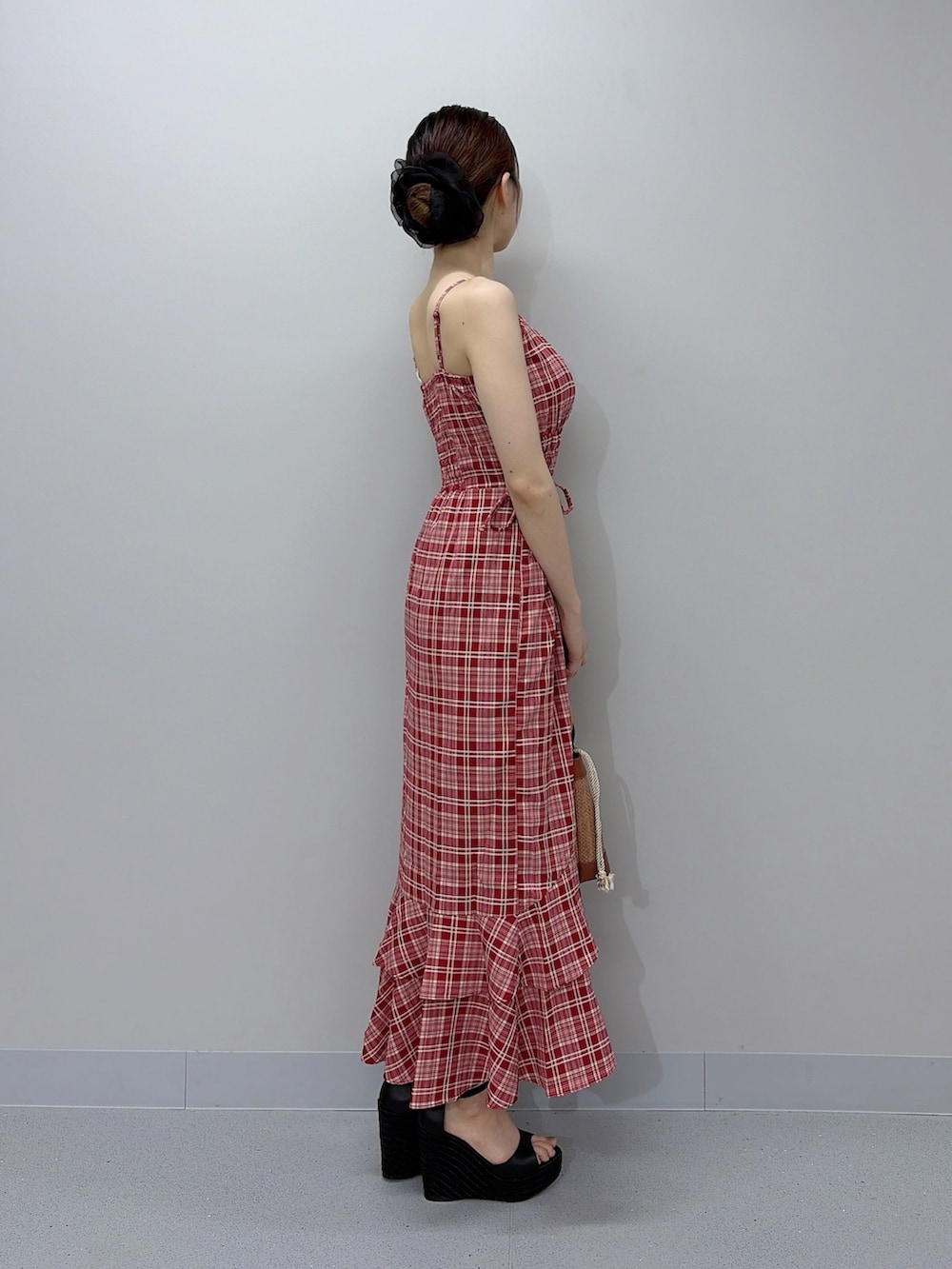 レッド系のワンピース、ブラウン系のハンドバッグ、ブラック系のサンダルを着用したレディースの夏コーディネートの4枚目の写真