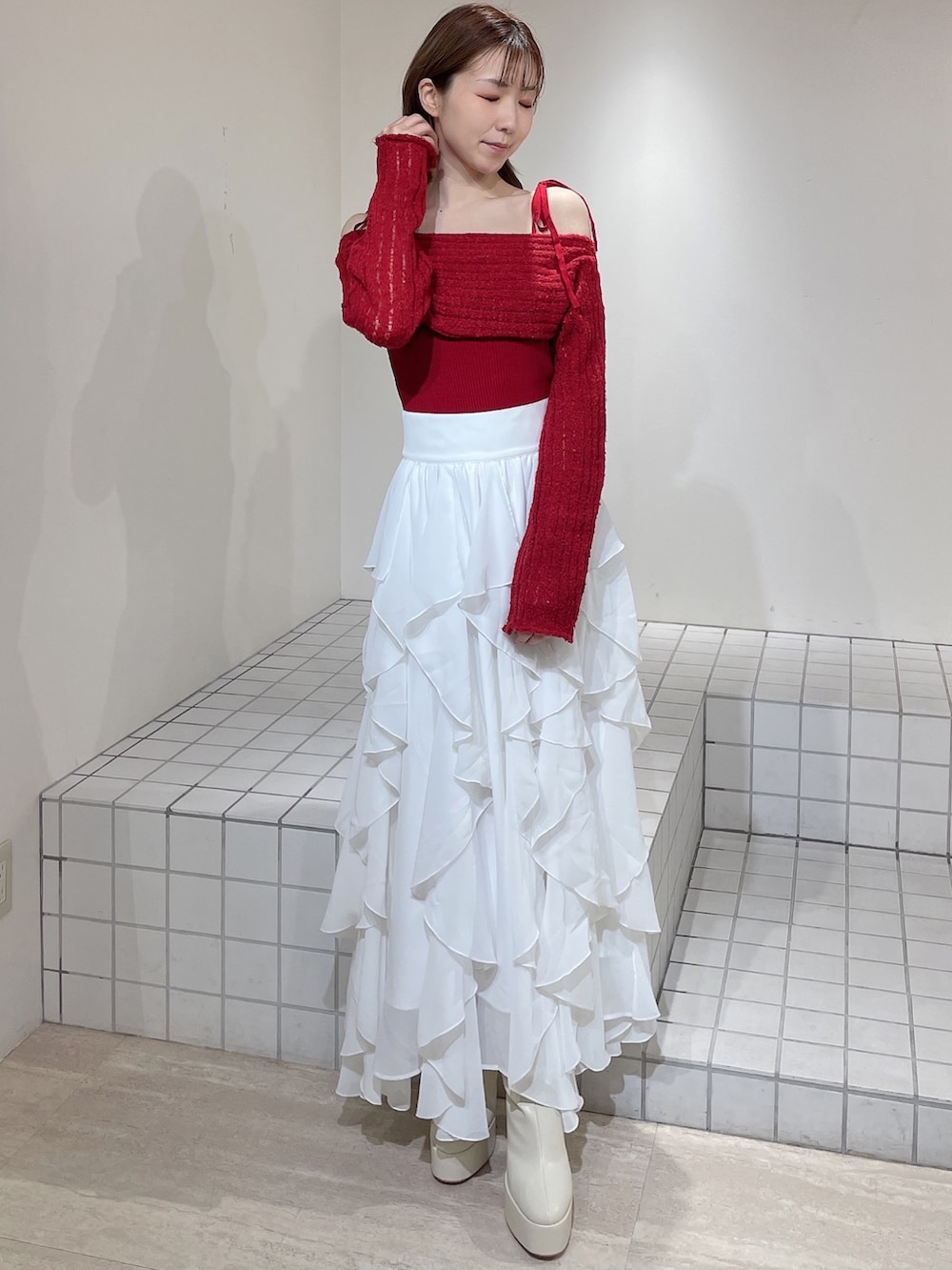 ブルー系のテーラードジャケット、レッド系のニット/セーター、ホワイト系のスカートを着用したレディースの冬コーディネートの5枚目の写真