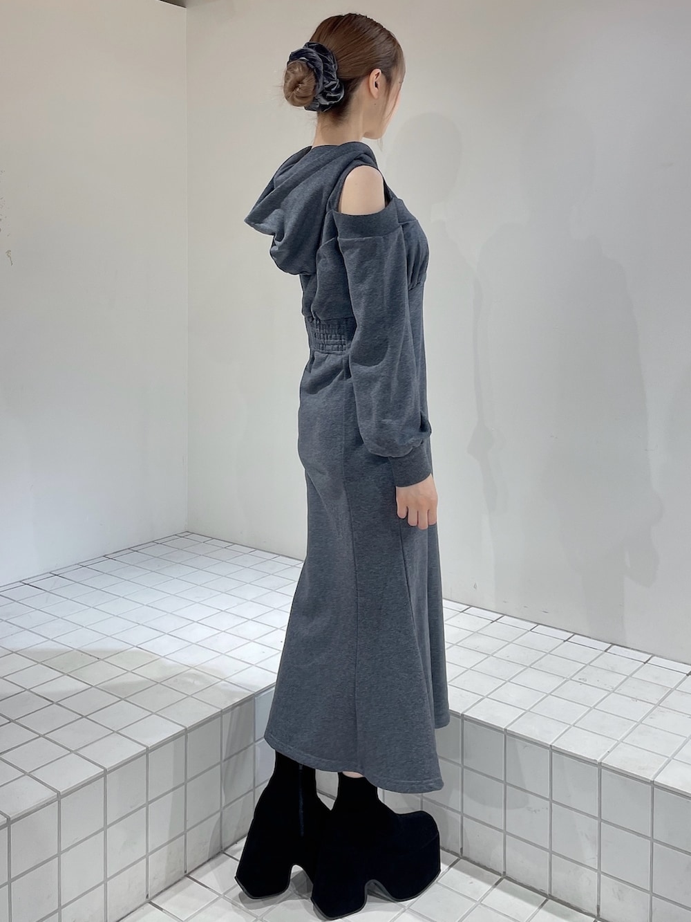 グレー系のワンピース、ブラック系のブーツ、グレー系のシュシュを着用したレディースの秋コーディネートの2枚目の写真