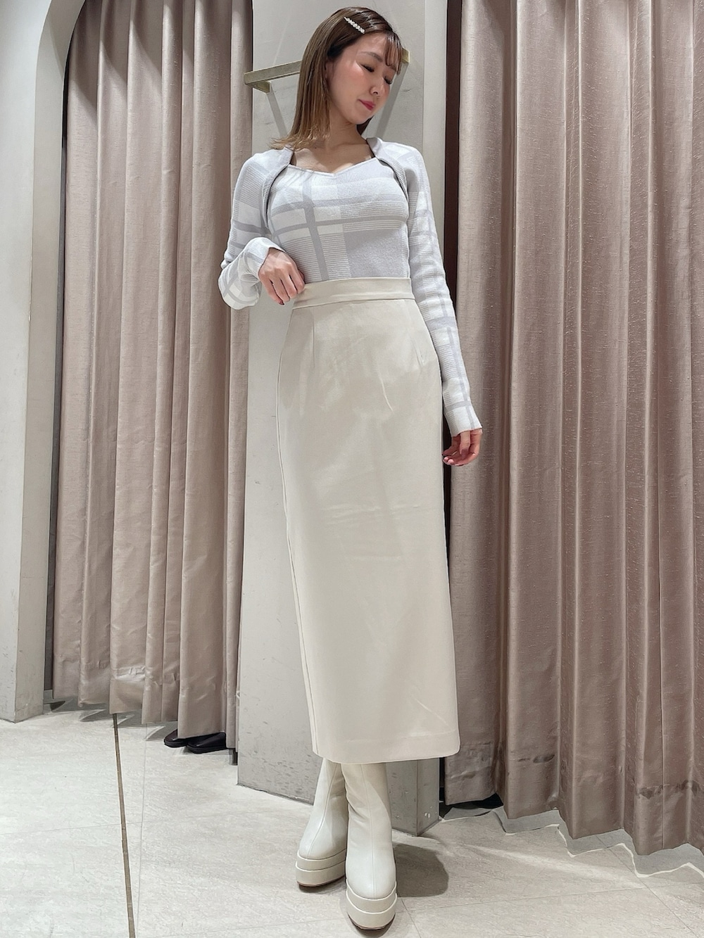 グレー系のニット/セーター、ホワイト系のスカート、ホワイト系のブーツを着用したレディースの冬コーディネートの2枚目の写真