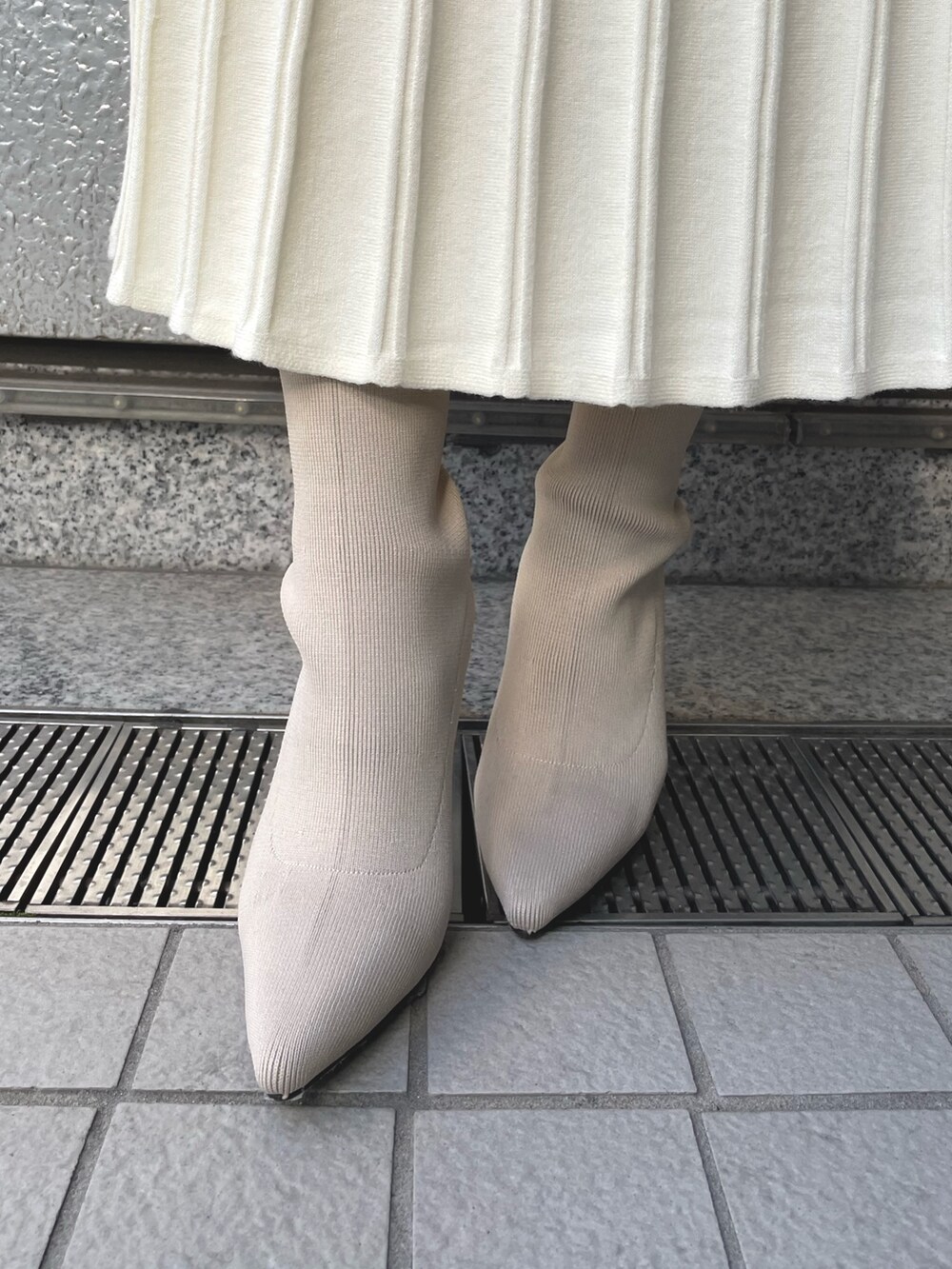 ホワイト系のブーツ、ブラック系のハンドバッグ、グレー系のその他アウターを着用したレディースの冬コーディネートの7枚目の写真