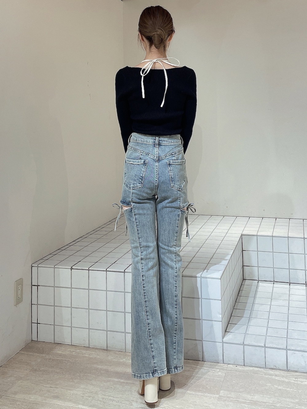 ブラック系のニット/セーター、ブルー系のデニムパンツ、ホワイト系のブーツを着用したレディースの冬コーディネートの4枚目の写真