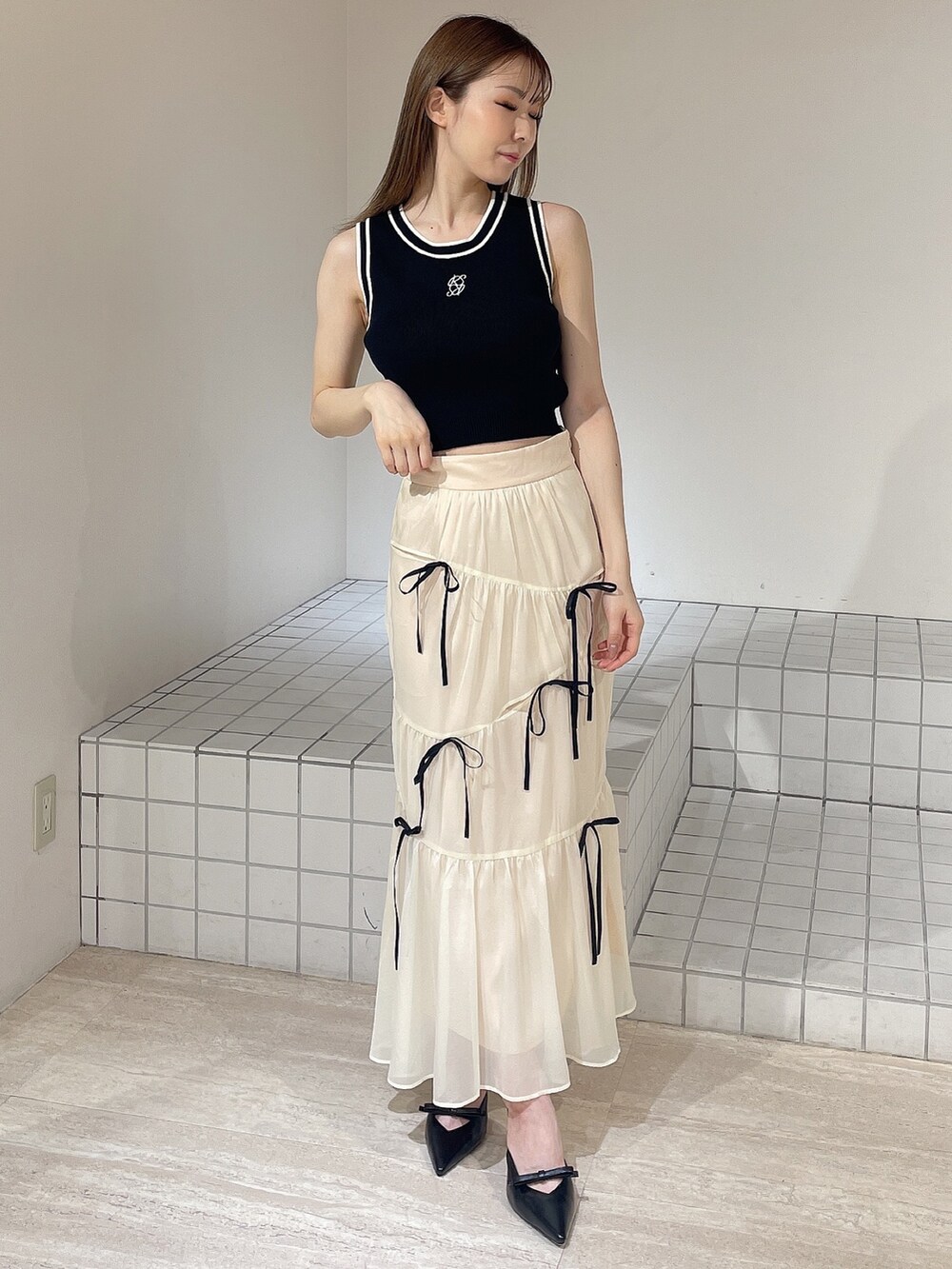 ブラック系のパンプス、ホワイト系のスカート、ブラック系のタンクトップを着用したレディースの夏コーディネートの2枚目の写真