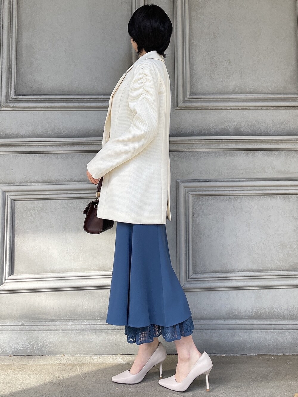 ホワイト系のテーラードジャケット、ブラウン系のハンドバッグ、ホワイト系のパンプスを着用したレディースの春コーディネートの2枚目の写真