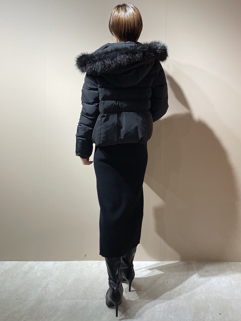 ブラック系のワンピース、ブラック系のダウンジャケット/コート、ブラック系のブーツを着用したレディースの秋コーディネートの6枚目の写真