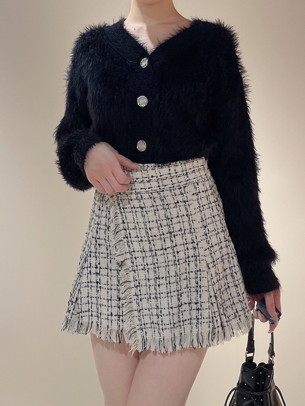 ブラック系のハンドバッグ、ブラック系のカーディガン/ボレロ、ホワイト系のスカートを着用したレディースの秋コーディネートの5枚目の写真