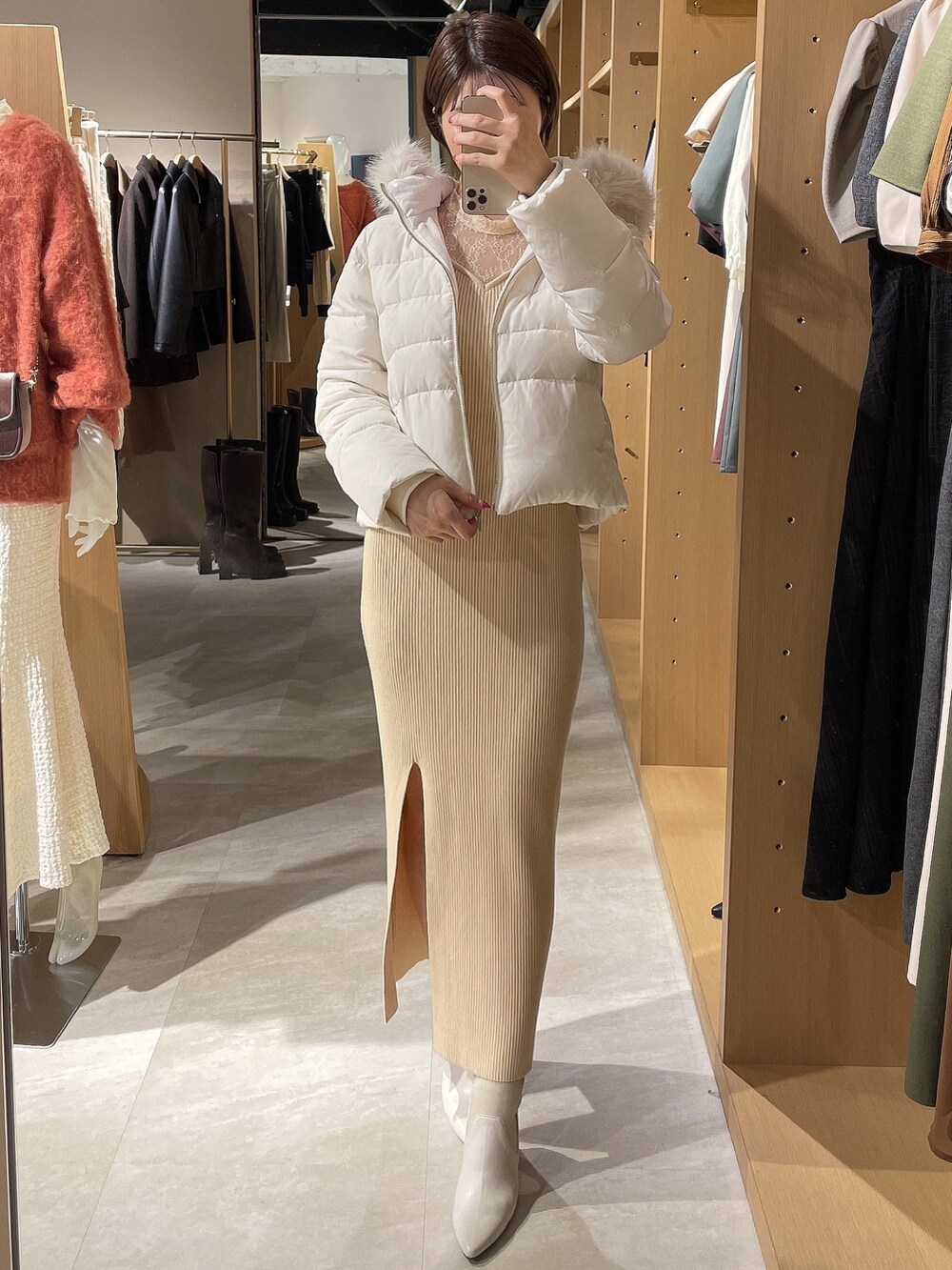ホワイト系のダウンジャケット/コート、ホワイト系のワンピース、ホワイト系のブーツを着用したレディースの秋コーディネートの6枚目の写真