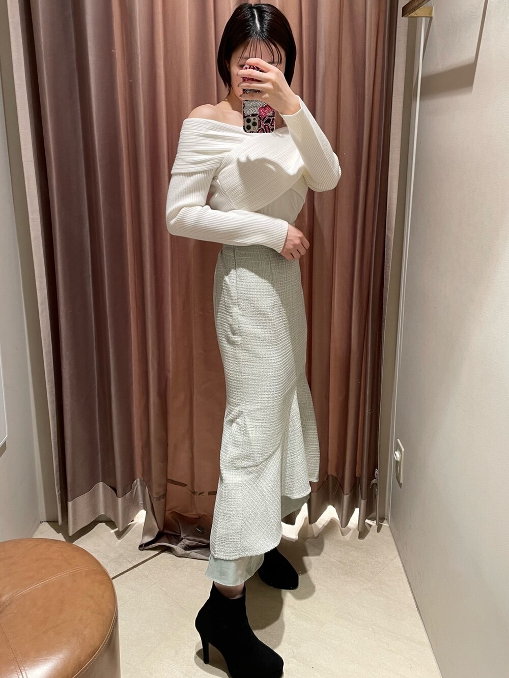 ホワイト系のニット/セーター、グリーン系のスカート、ブラック系のブーツを着用したレディースの冬コーディネートの2枚目の写真