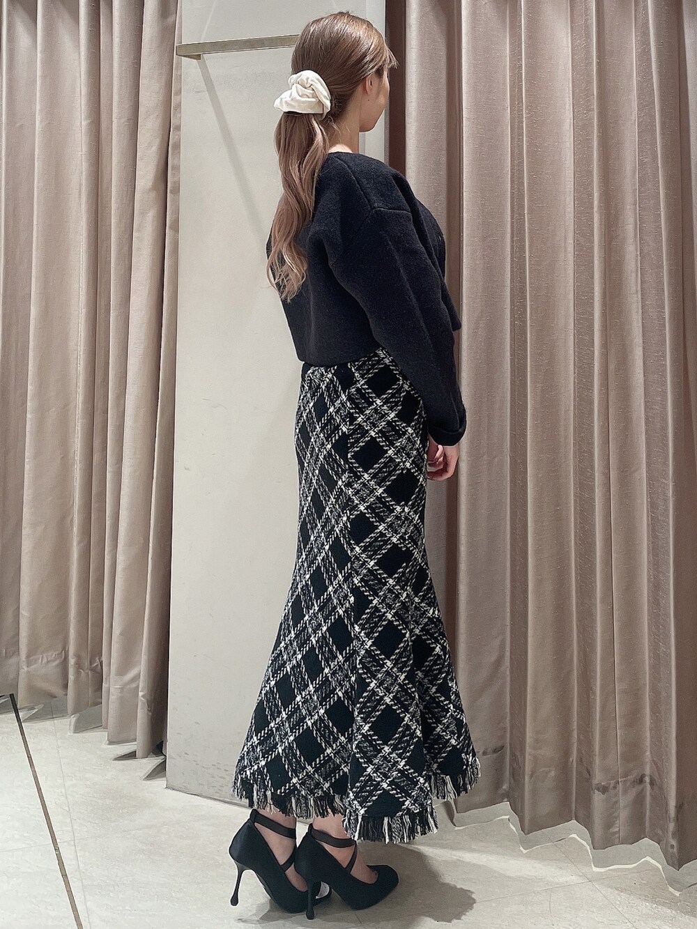 グレー系のカーディガン/ボレロ、ブラック系のワンピース、ブラック系のパンプスを着用したレディースの秋コーディネートの2枚目の写真