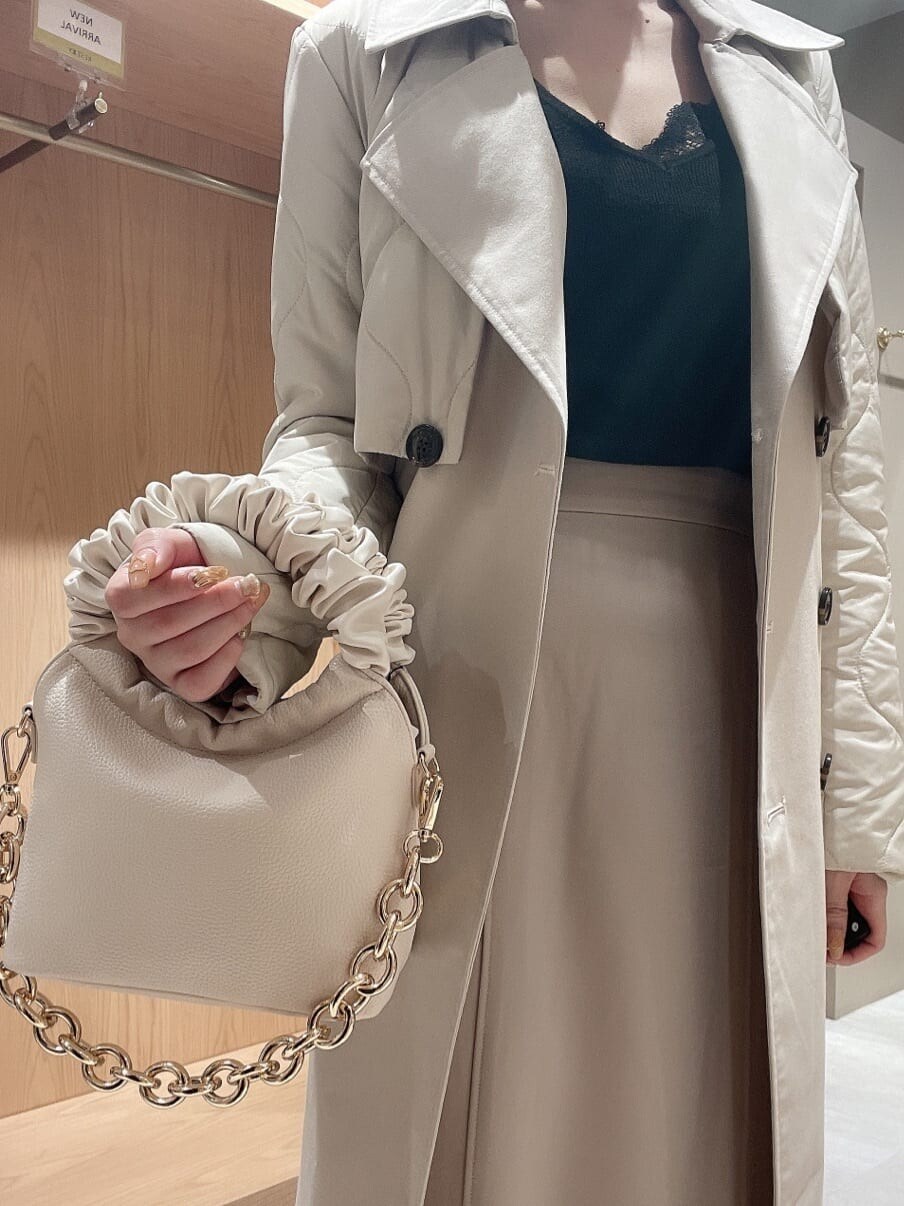 ブラック系のパンプス、ホワイト系のハンドバッグ、ホワイト系のトレンチコートを着用したレディースの秋コーディネートの4枚目の写真