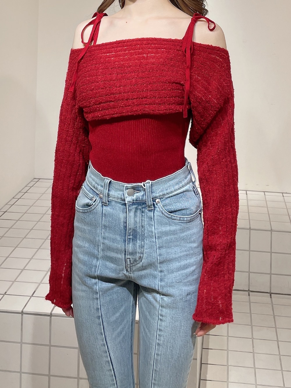 レッド系のニット/セーター、ブルー系のデニムパンツ、ホワイト系のブーツを着用したレディースの冬コーディネートの5枚目の写真