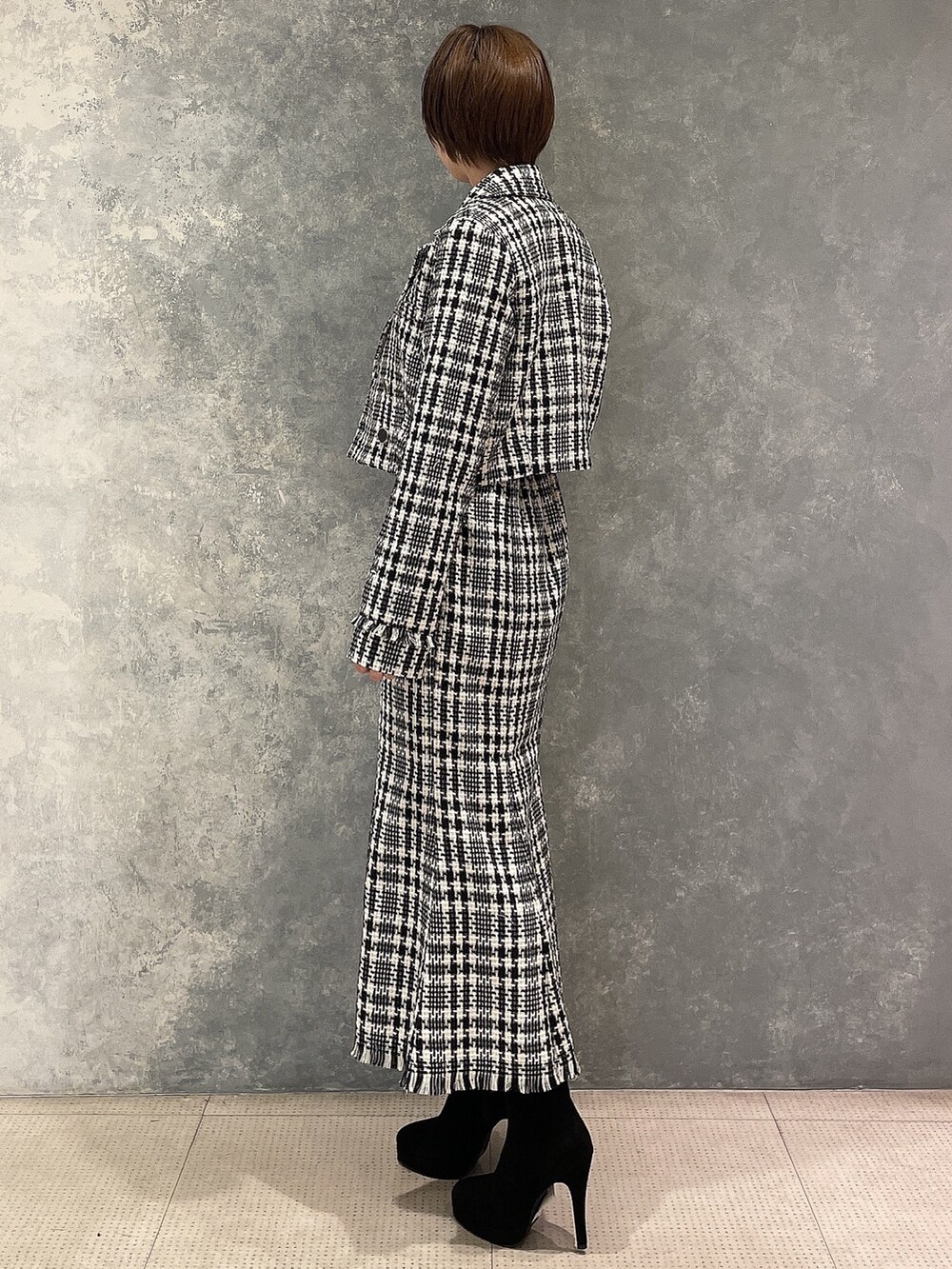 ブラック系のブーツ、ブラック系のスカート、ブラック系のテーラードジャケットを着用したレディースの夏コーディネートの3枚目の写真