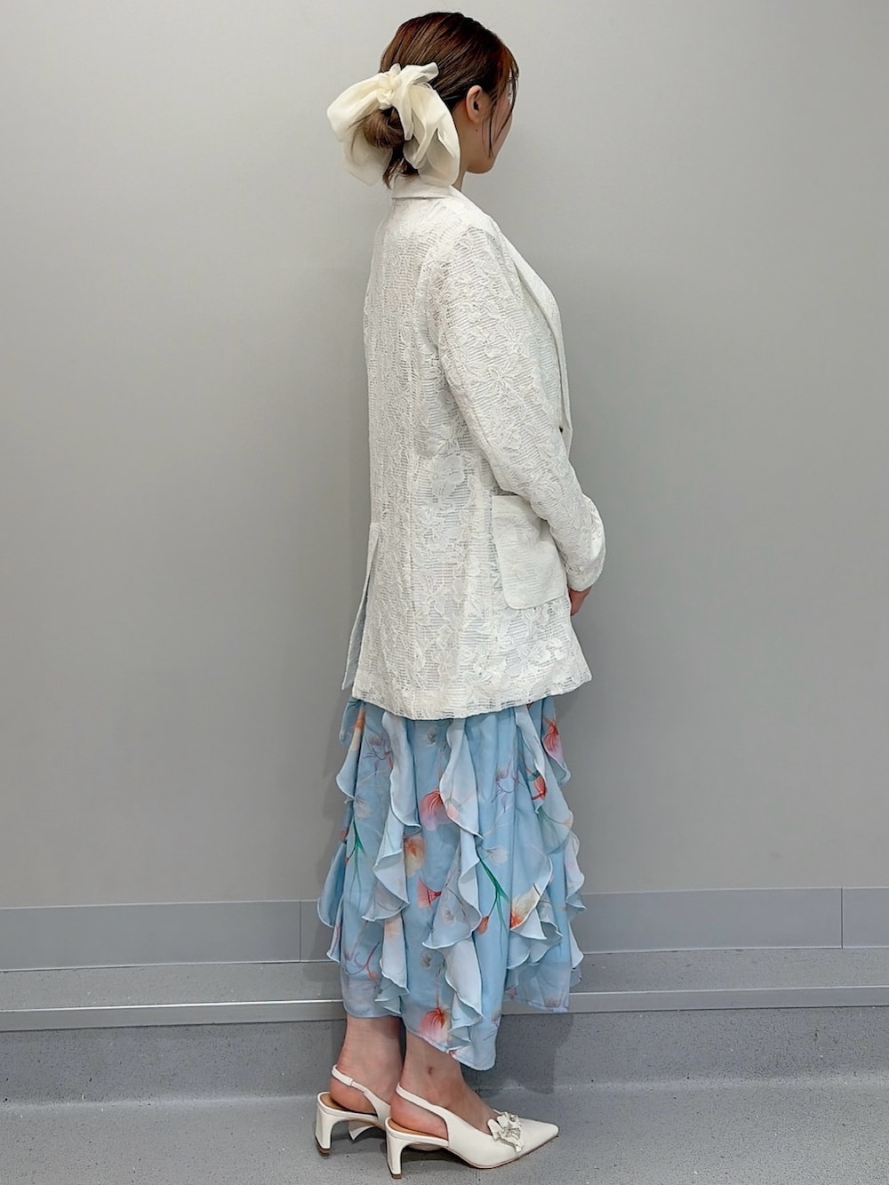 ホワイト系のテーラードジャケット、ブルー系のワンピース、ホワイト系のパンプスを着用したレディースの冬コーディネートの3枚目の写真