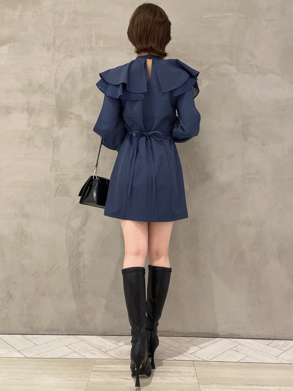 ブラック系のハンドバッグ、ブラック系のブーツ、ブルー系のワンピースを着用したレディースの冬コーディネートの3枚目の写真