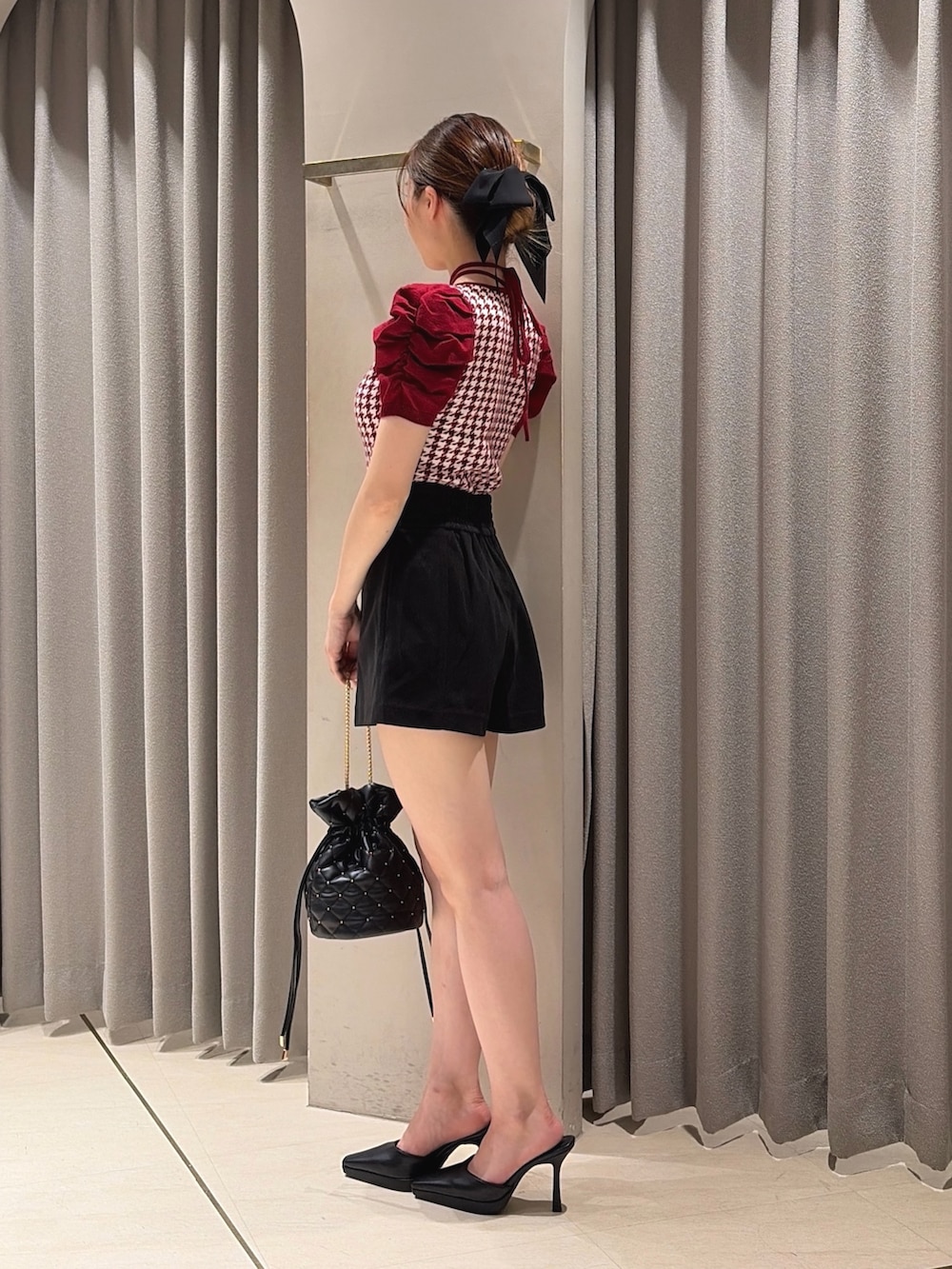 レッド系のニット/セーター、ブラック系のその他パンツ、ブラック系のハンドバッグを着用したレディースの夏コーディネートの2枚目の写真