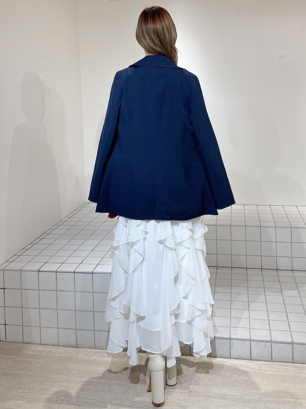 ブルー系のテーラードジャケット、レッド系のニット/セーター、ホワイト系のスカートを着用したレディースの冬コーディネートの4枚目の写真