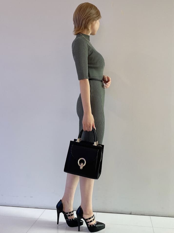 ブラック系のハンドバッグ、グリーン系のワンピース、ブラック系のパンプスを着用したレディースの夏コーディネートの4枚目の写真