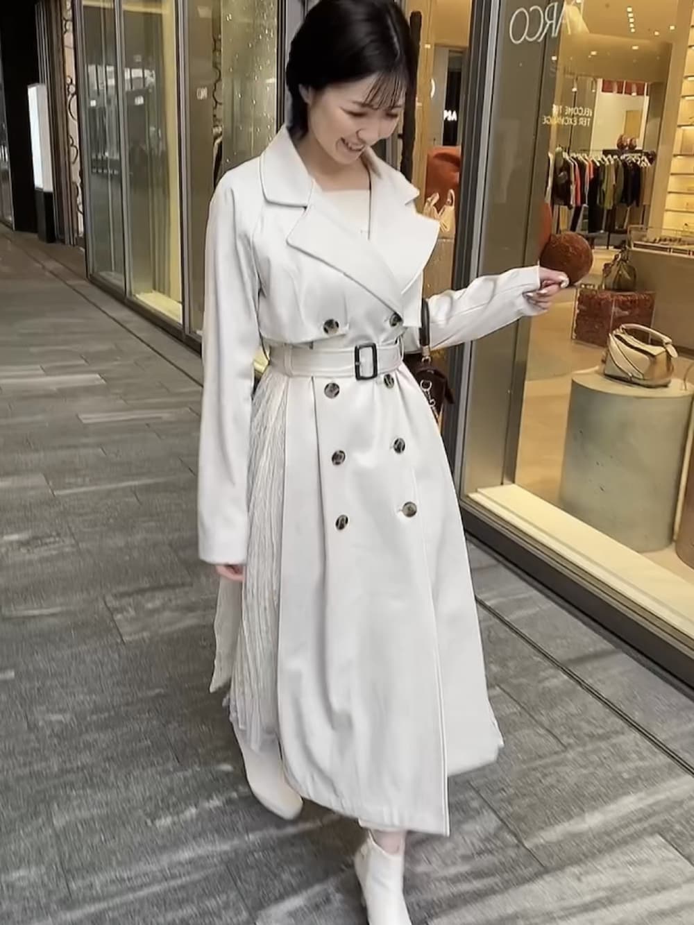 ブラウン系のハンドバッグ、ホワイト系のトレンチコート、ホワイト系のブーツを着用したレディースの冬コーディネートの2枚目の写真