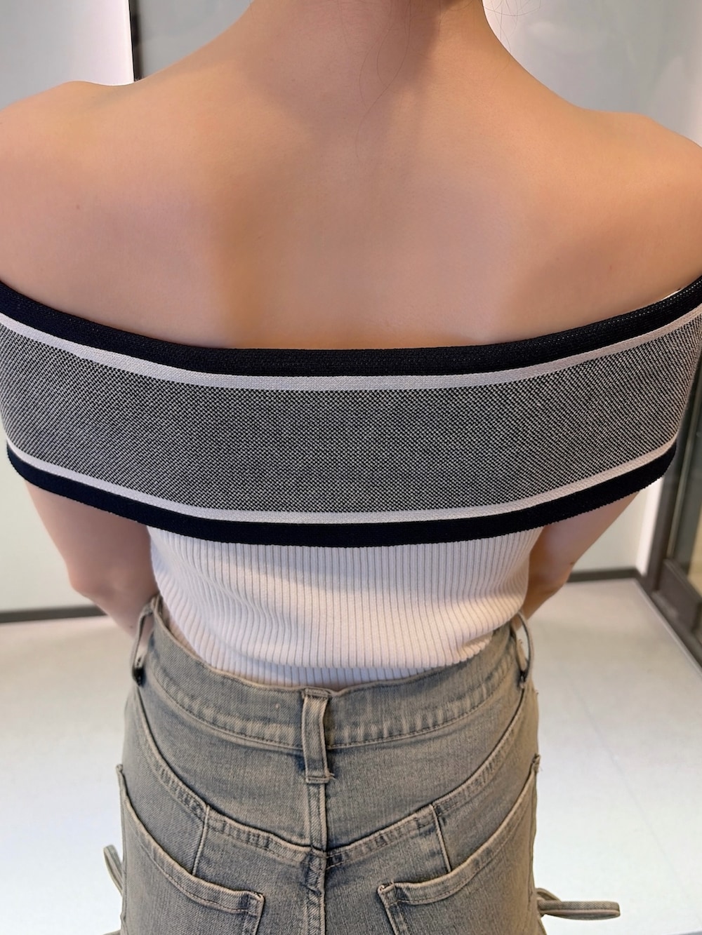 ホワイト系のニット/セーター、ブルー系のデニムパンツ、ホワイト系のハンドバッグを着用したレディースの夏コーディネートの6枚目の写真