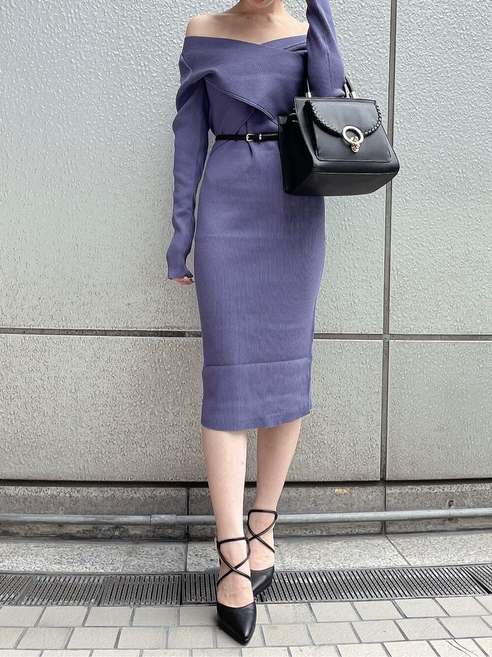 ブラック系のライダースジャケット、ブラック系のハンドバッグ、ブルー系のワンピースを着用したレディースの秋コーディネートの2枚目の写真