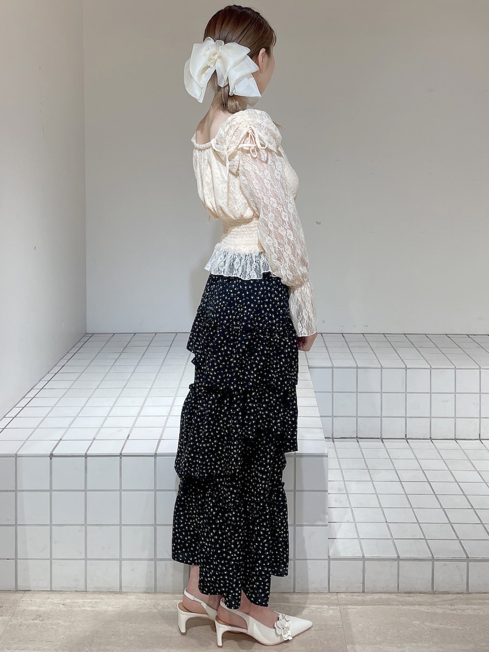 オレンジ系のシャツ/ブラウス、ブラック系のスカート、ホワイト系のパンプスを着用したレディースの春コーディネートの3枚目の写真