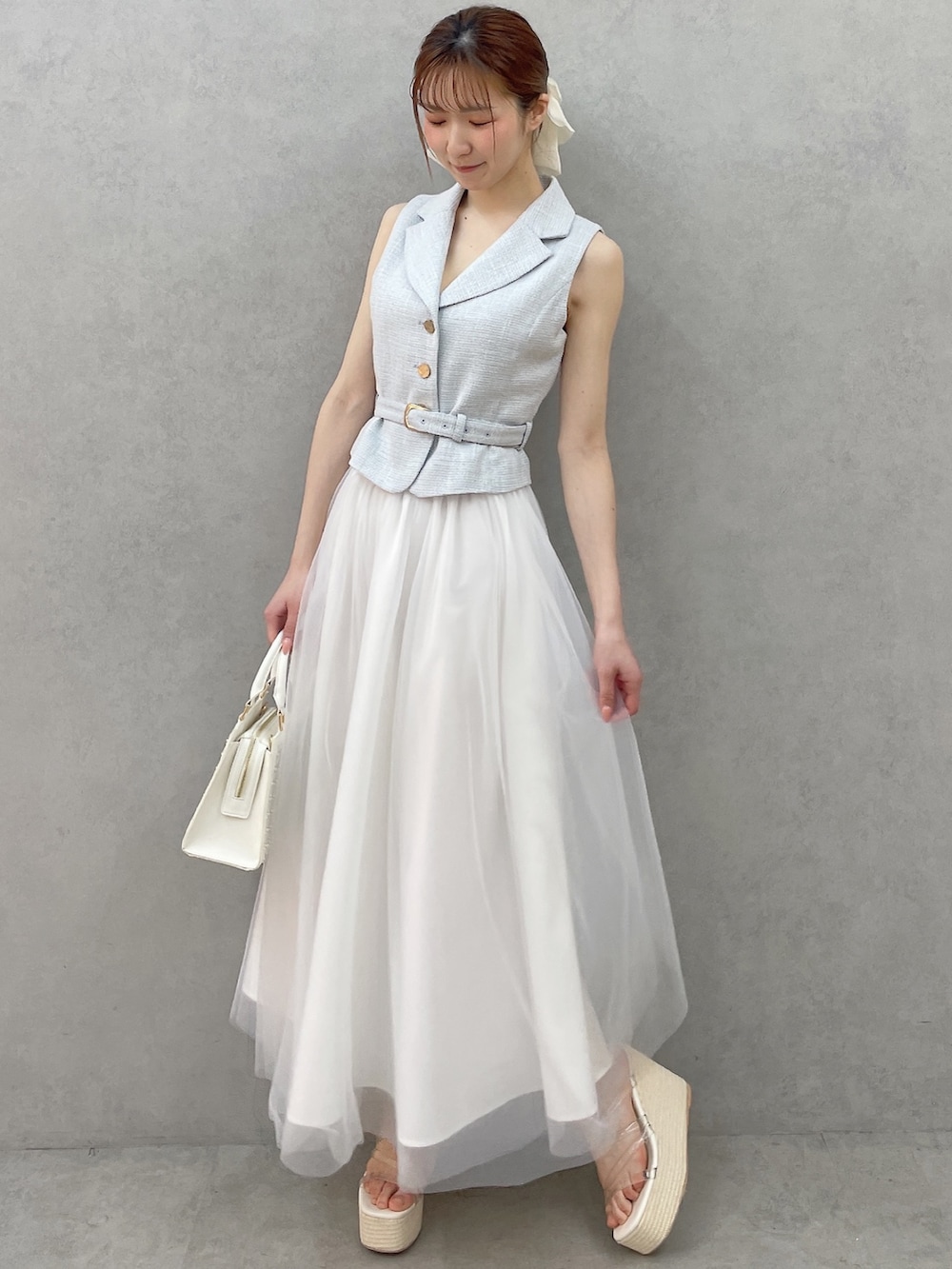 ブルー系のワンピース、ホワイト系のハンドバッグ、ホワイト系のサンダルを着用したレディースの春コーディネートの2枚目の写真