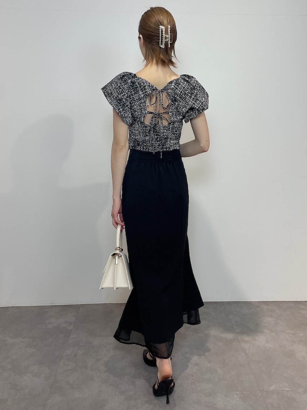 ブラック系のシャツ/ブラウス、ホワイト系のハンドバッグ、ブラック系のパンプスを着用したレディースの春コーディネートの5枚目の写真