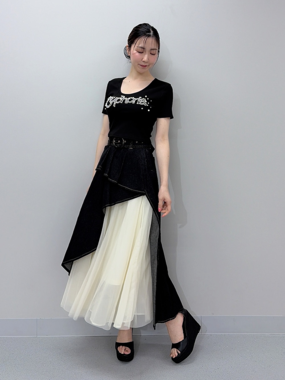 ブラック系のTシャツ/カットソー、ブラック系のスカート、ブラック系のサンダルを着用したレディースの夏コーディネートの2枚目の写真