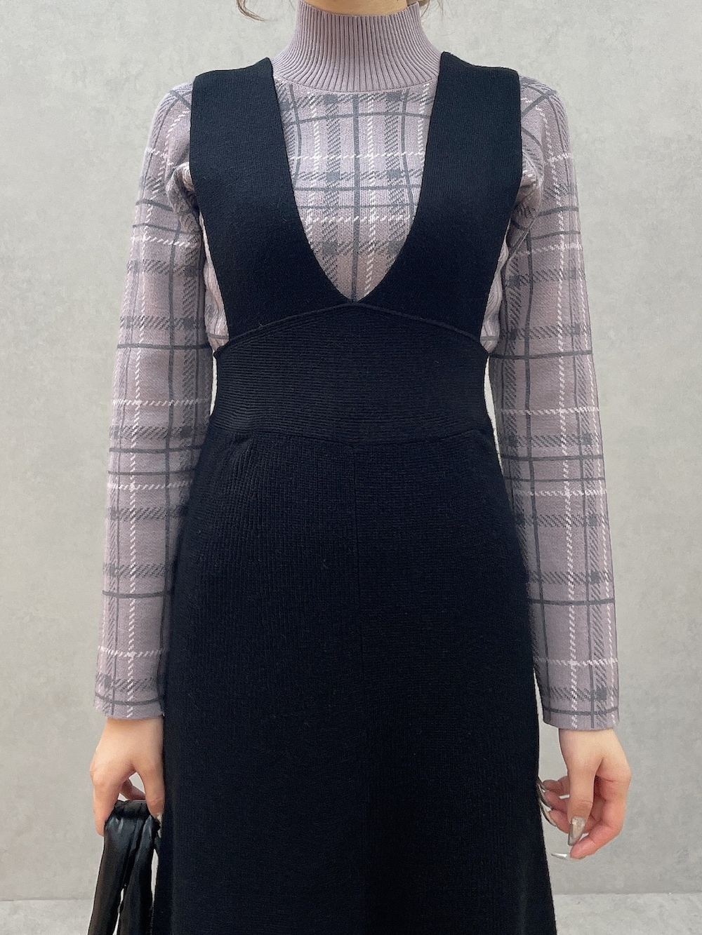 パープル系のニット/セーター、ブラック系のブーツ、ブラック系のジャンパースカートを着用したレディースの秋コーディネートの5枚目の写真