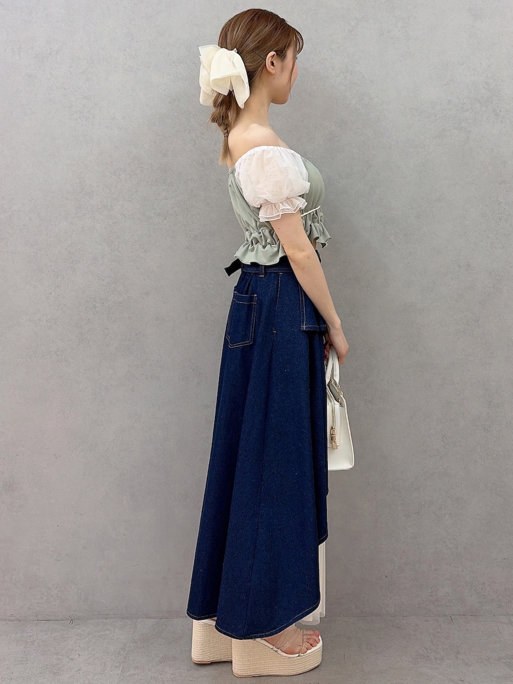 ホワイト系のハンドバッグ、グリーン系のシャツ/ブラウス、ブルー系のスカートを着用したレディースの春コーディネートの2枚目の写真