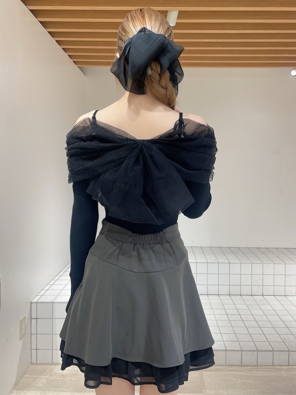 グレー系のスカート、ブラック系のニット/セーター、ブラック系のブーツを着用したレディースの春コーディネートの5枚目の写真