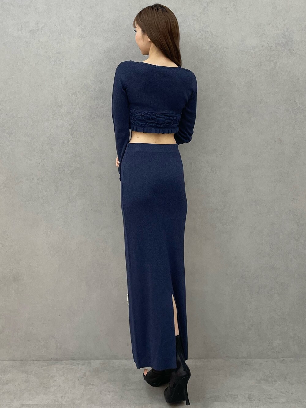 ブルー系のニット/セーター、ブルー系のスカート、ホワイト系のハンドバッグを着用したレディースの春コーディネートの5枚目の写真