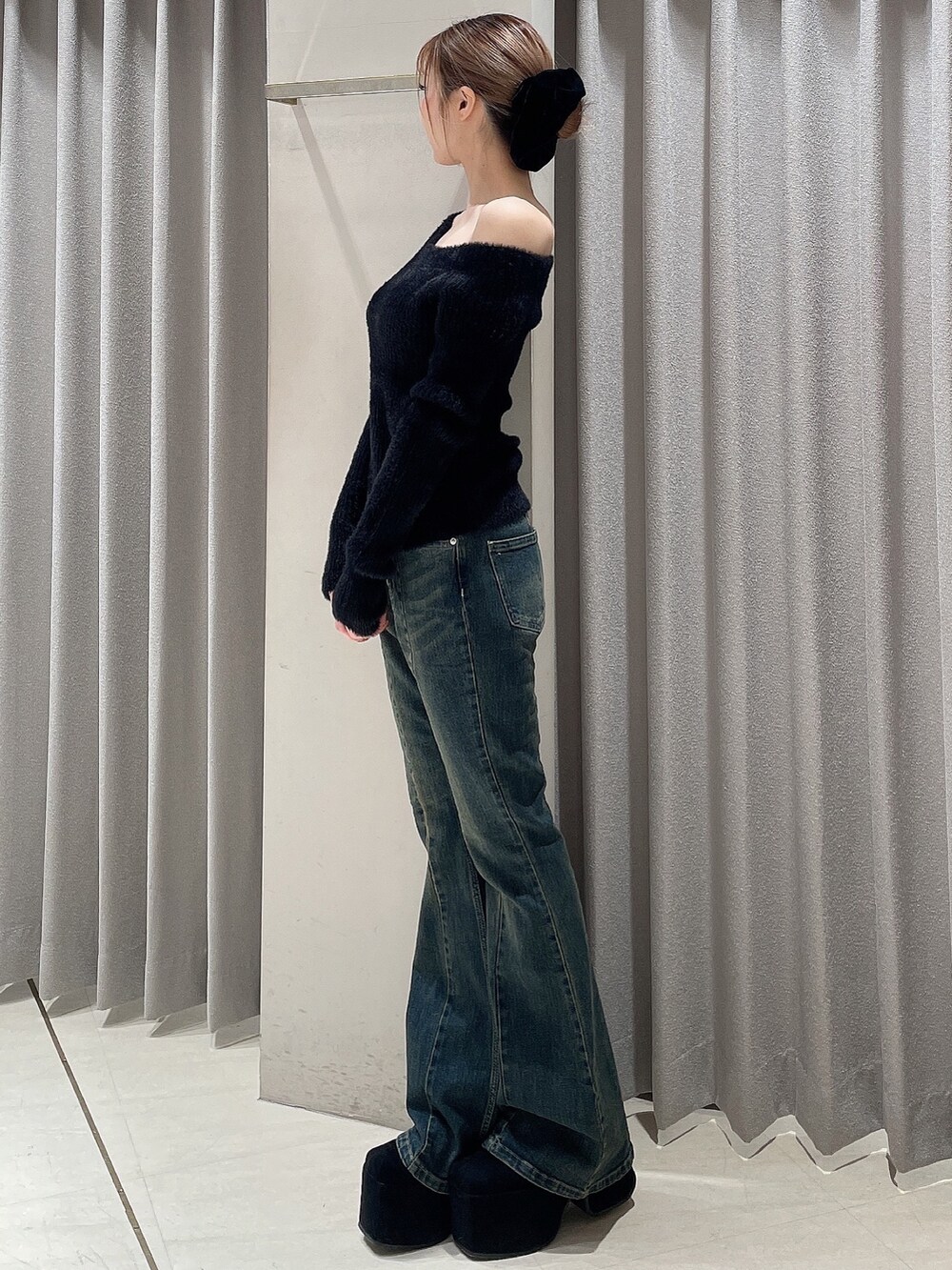 ブルー系のデニムパンツ、ブラック系のニット/セーター、ブラック系のブーツを着用したレディースの秋コーディネートの4枚目の写真