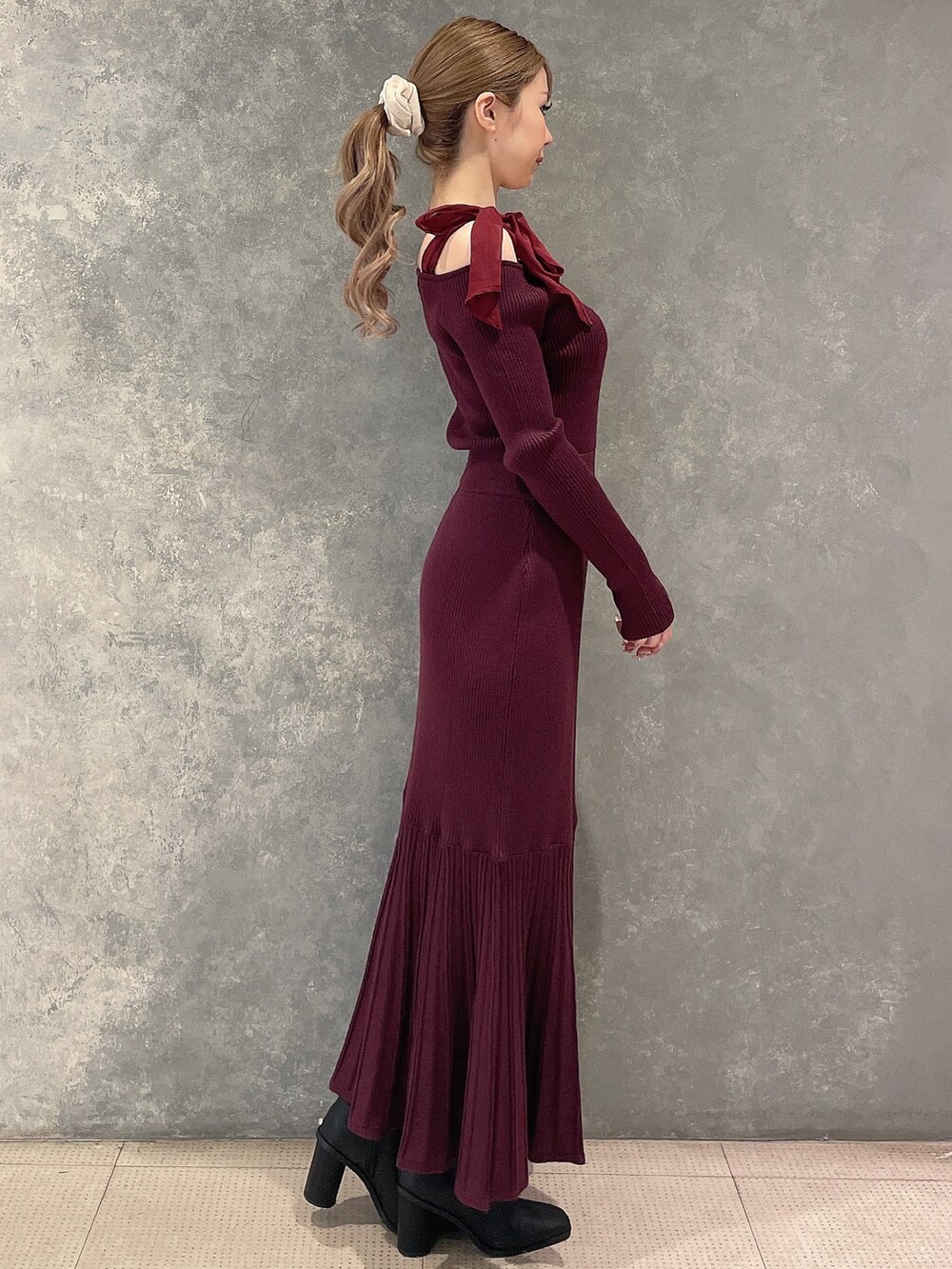 レッド系のワンピース、ブラック系のブーツを着用したレディースの秋コーディネートの3枚目の写真